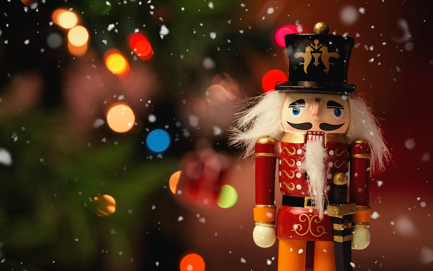 colorful wooden nutcracker soldier shown against Christmas tree bokeh