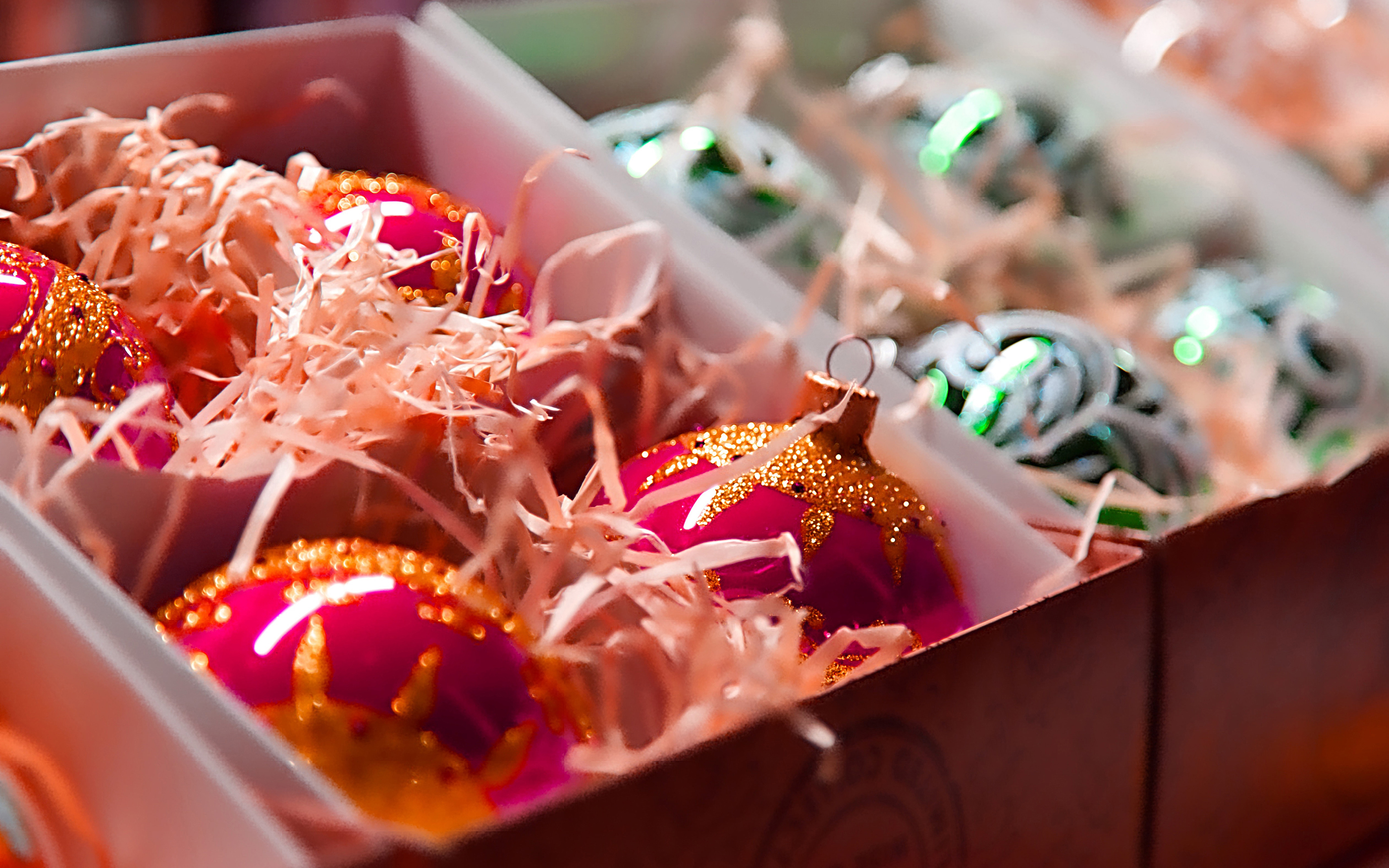 shiny, colorful Christmas ball ornaments stored in compartmented boxes, with paper grass
