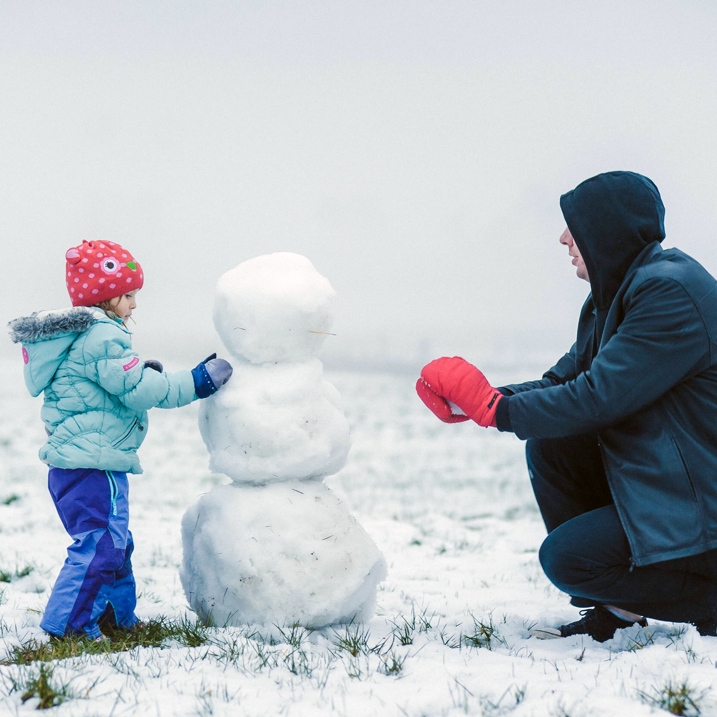 dad and child building snowman together
