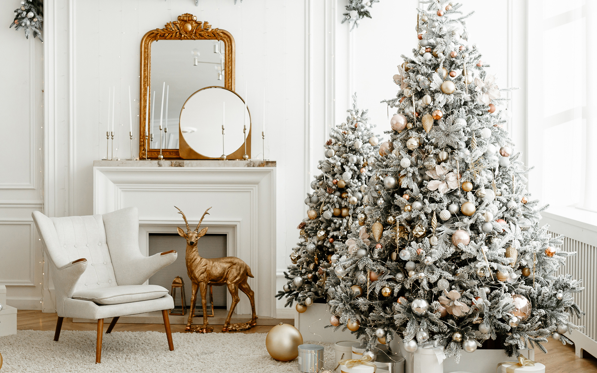 pair of flocked Christmas trees in an elegant white and gold living room