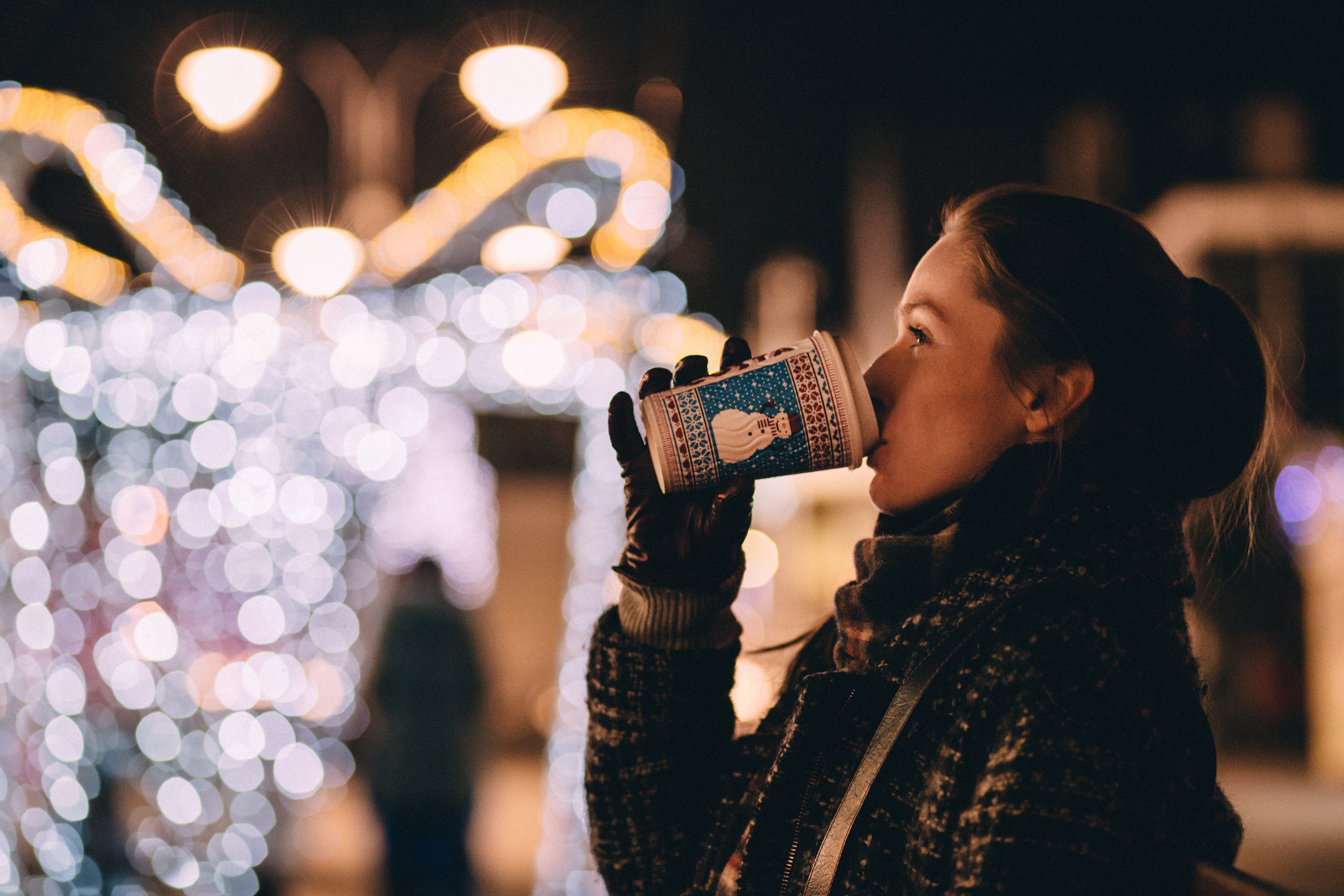 Woman Drinking Hot Coffee in front of Christmas Display