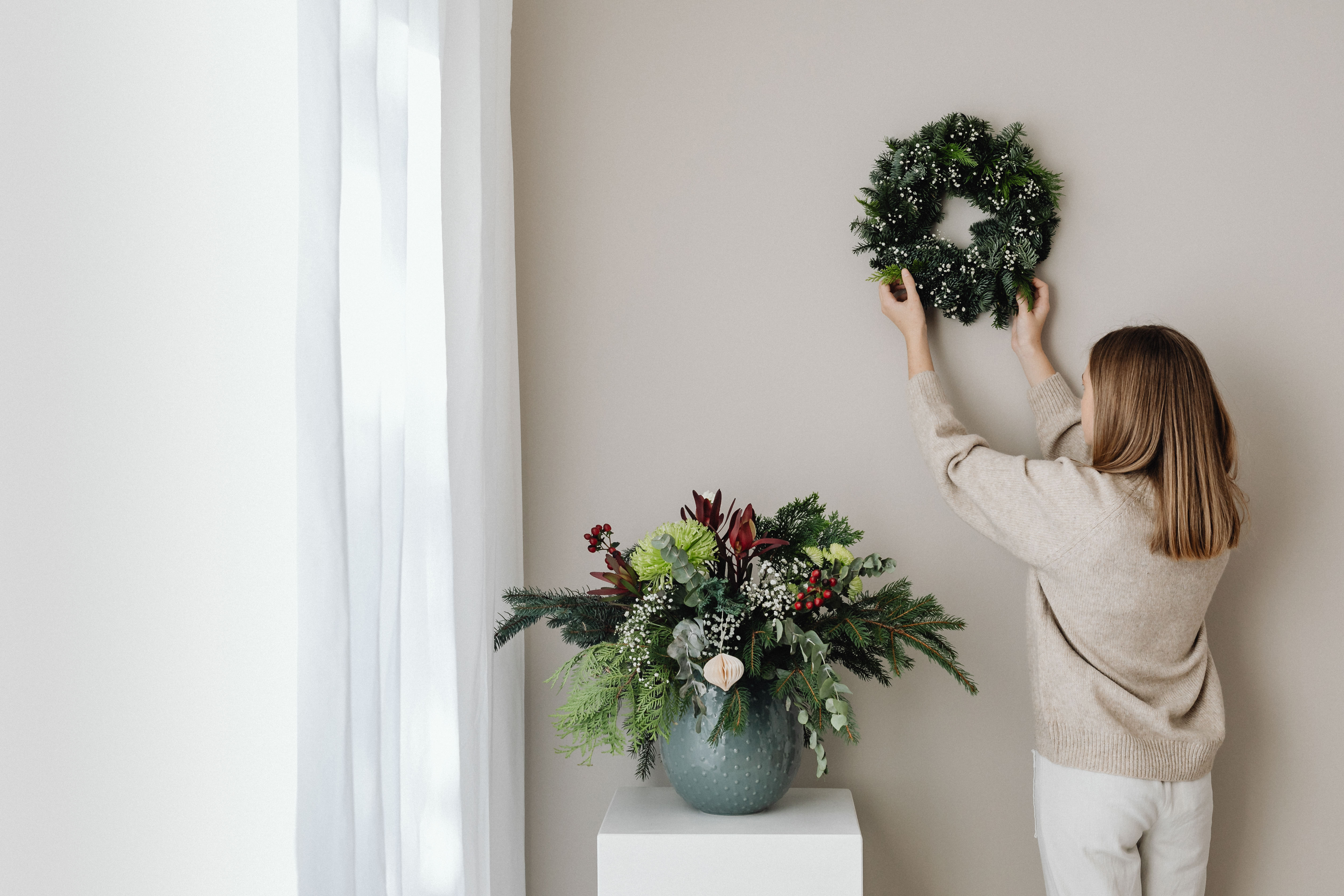 woman hanging wreath on living room wall