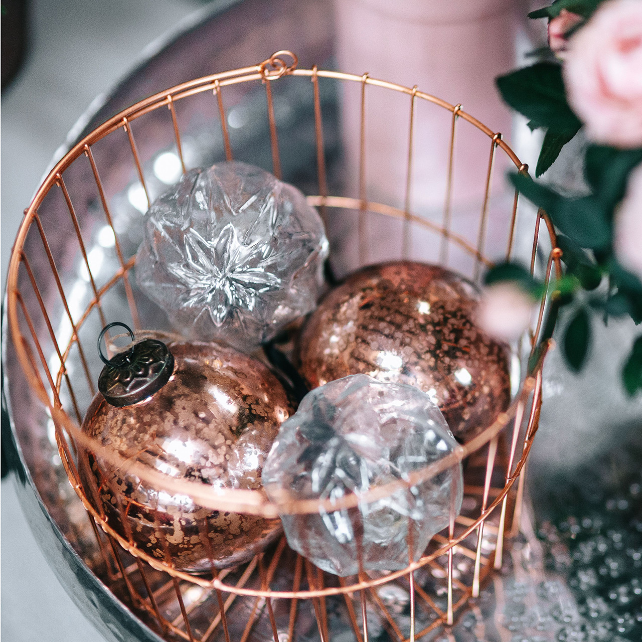 rose gold and crystal ornaments in copper wire basket