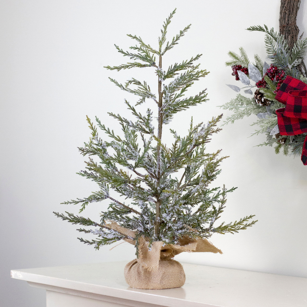 tabletop potted Christmas tree shown on a fireplace mantel