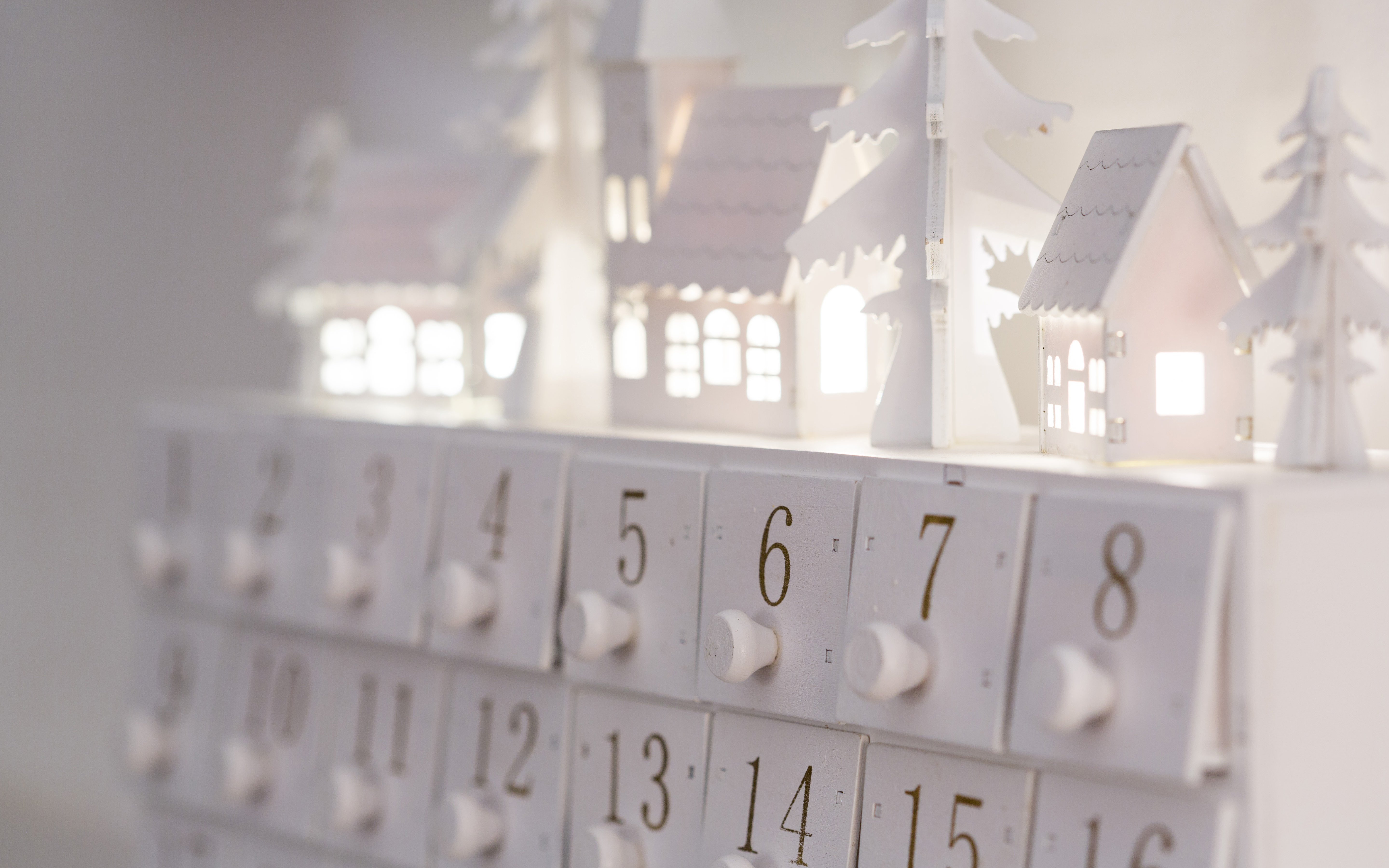 white advent calendar decorated with lighted miniature village